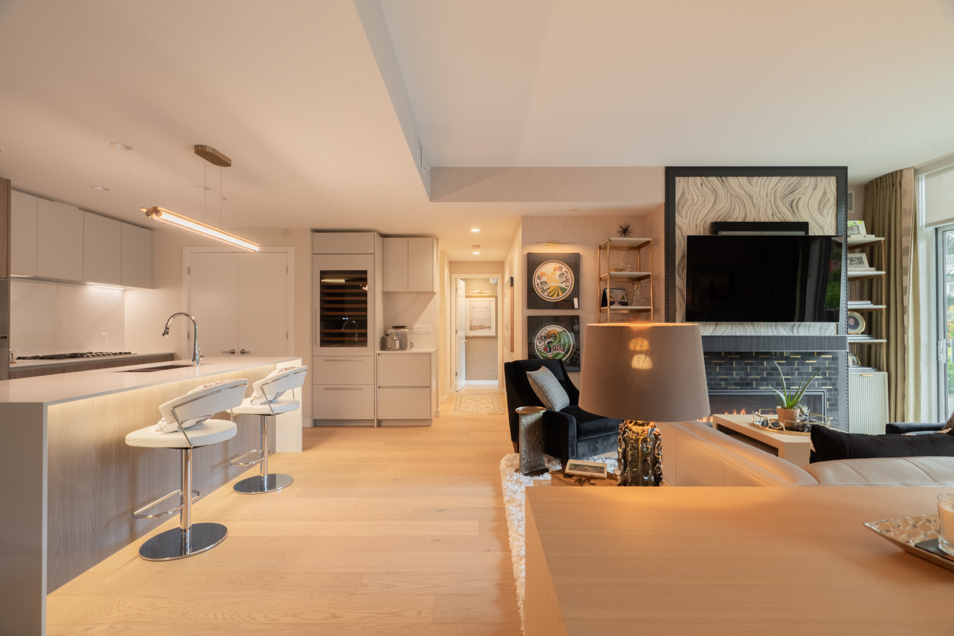Open kitchen and living space with island seating, oak floors, and a gas fireplace