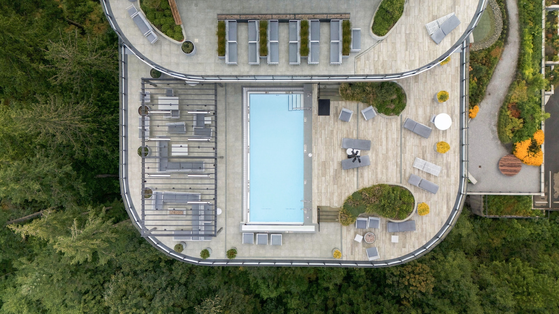 Aerial view of the rooftop pool, lounge chairs, and surrounding deck at One Bear Mountain