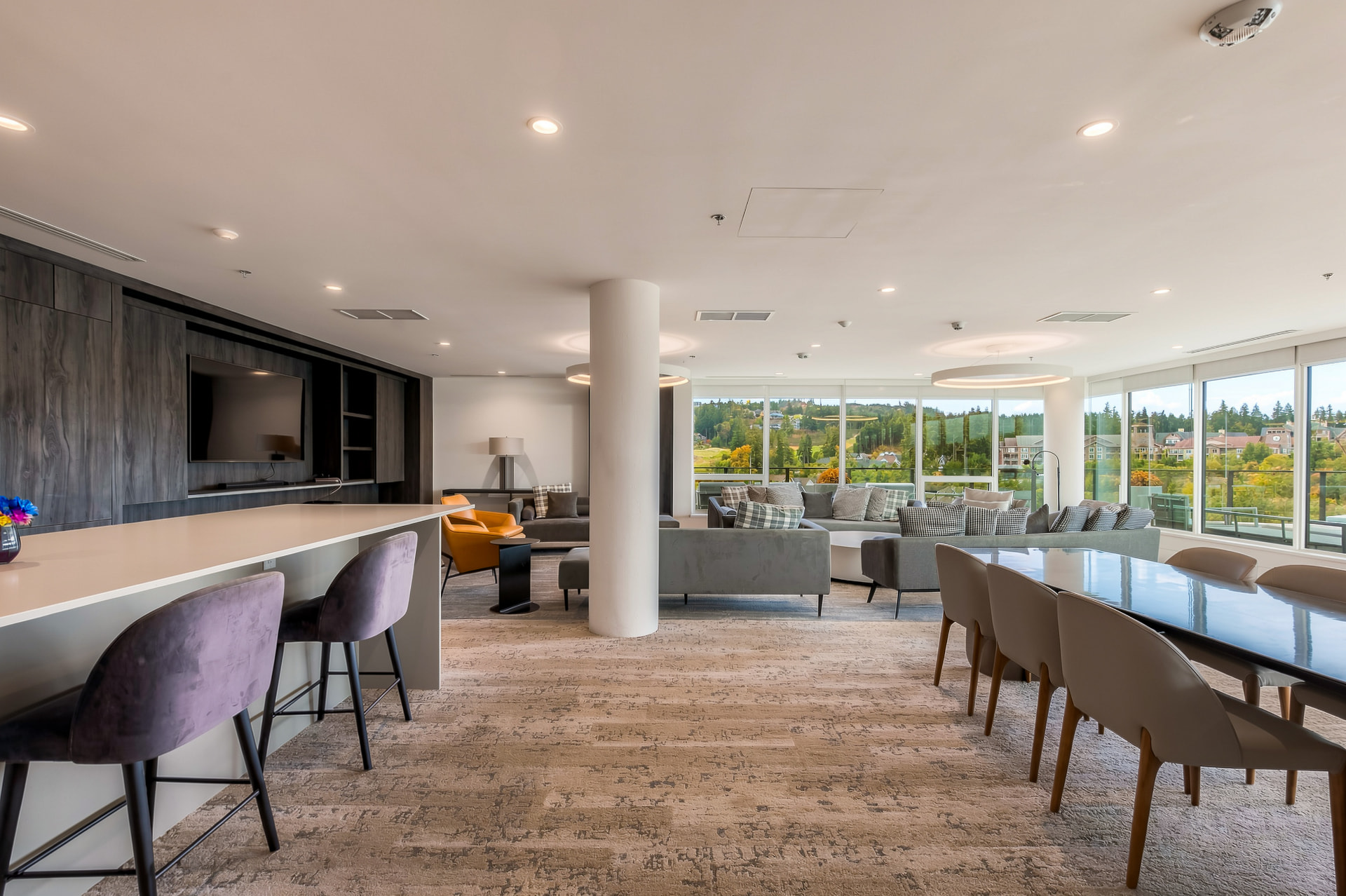Building lounge with bar seating, sofas, and mountain views through floor-to-ceiling windows